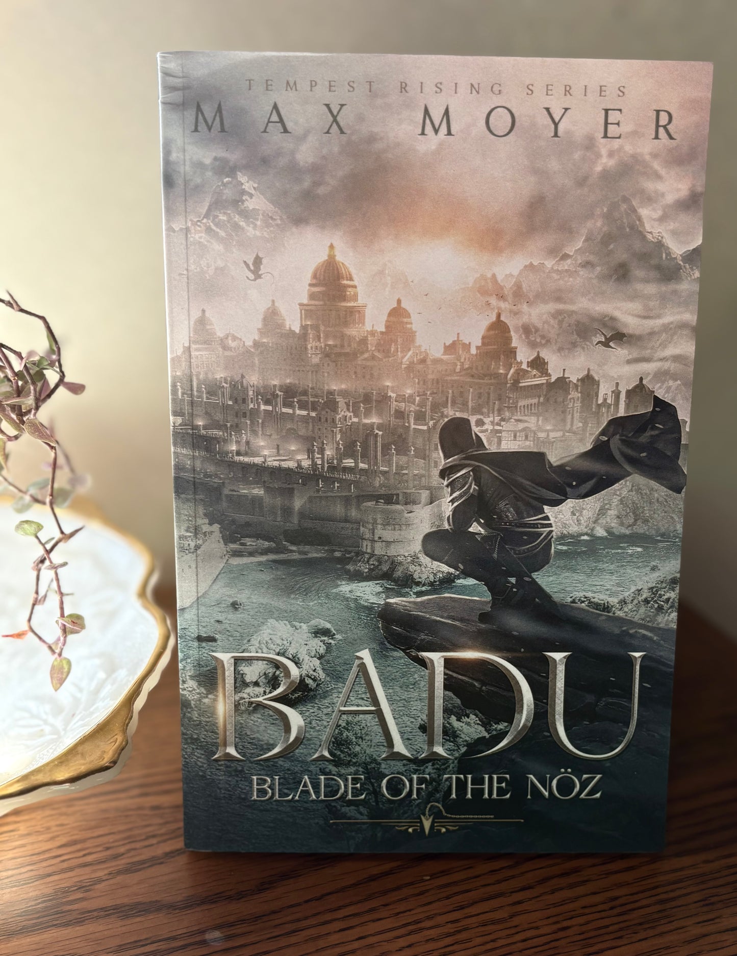 Book cover of 'Baidu: Blade of the Nóz' by Max Moyer on a wooden surface with decorative elements.