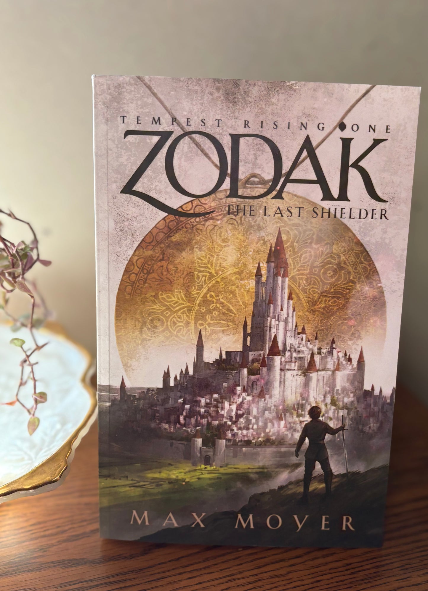 Book titled 'Zodak: The Last Shielder' by Max Mover on a wooden surface.