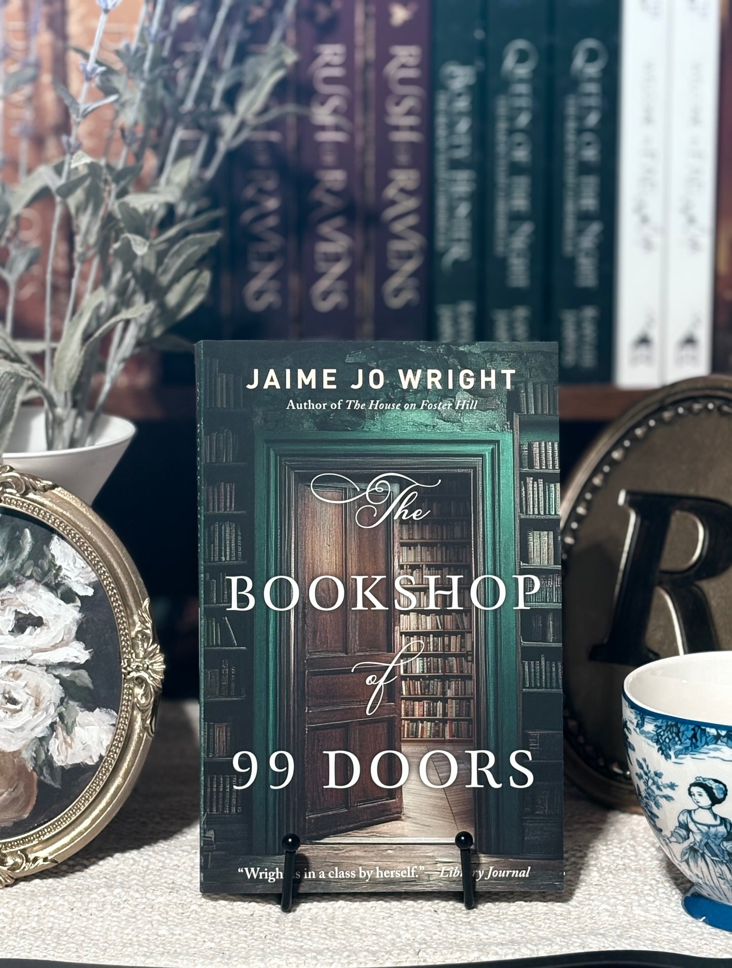 Book titled 'The Bookshop of 99 Doors' by Jaime Jo Wright on a table with decorative items.