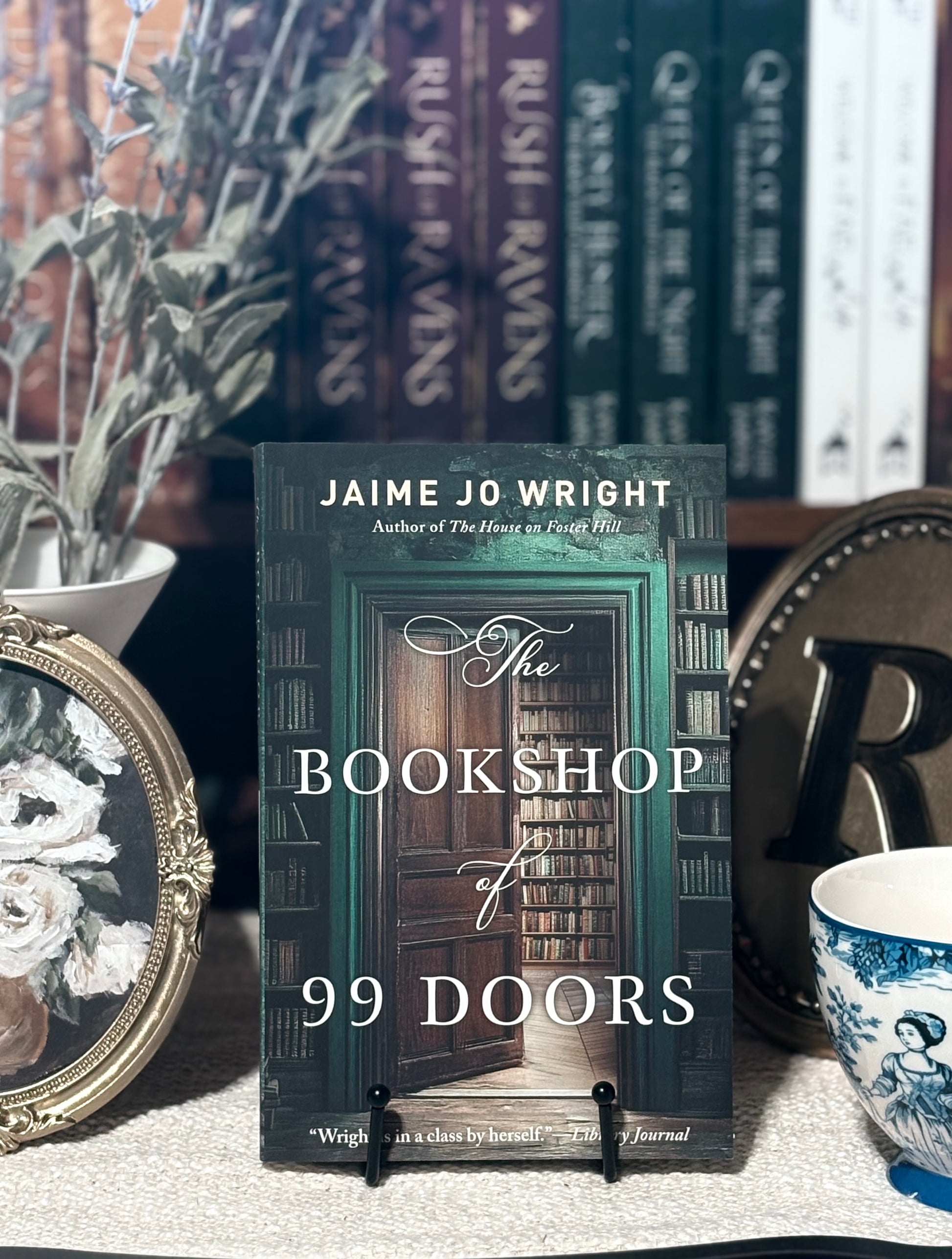 Book titled 'The Bookshop of 99 Doors' by Jaime Jo Wright on a table with decorative items.