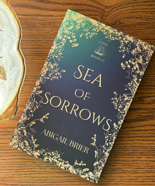 Book titled 'Sea of Sorrows' by Abigail Brier on a wooden surface